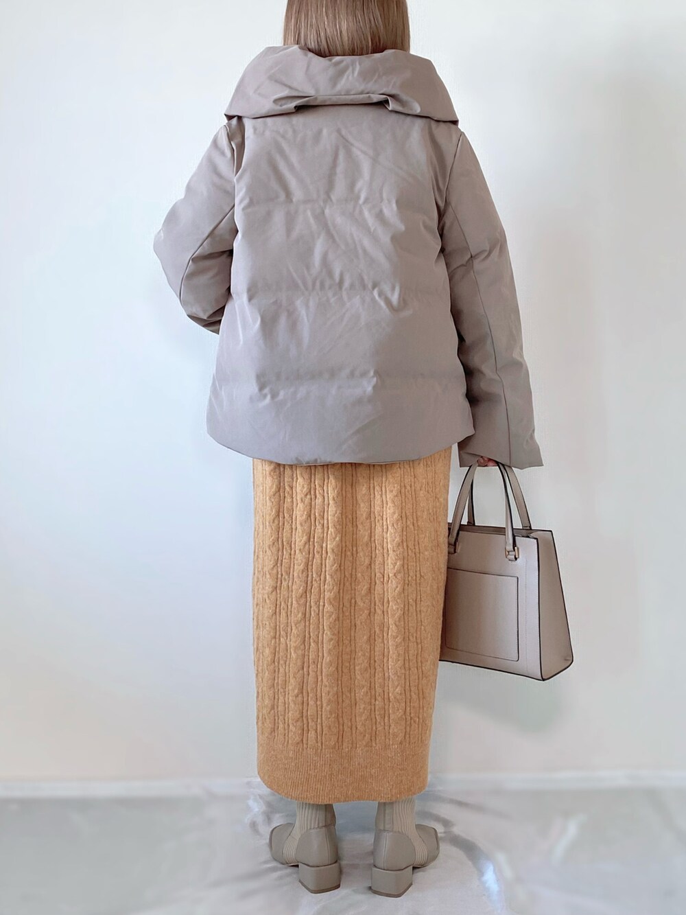 ブラウン系のダウンジャケット/コート、オレンジ系のワンピース、ベージュ系のバッグを着用したレディースの秋コーディネートの2枚目の写真