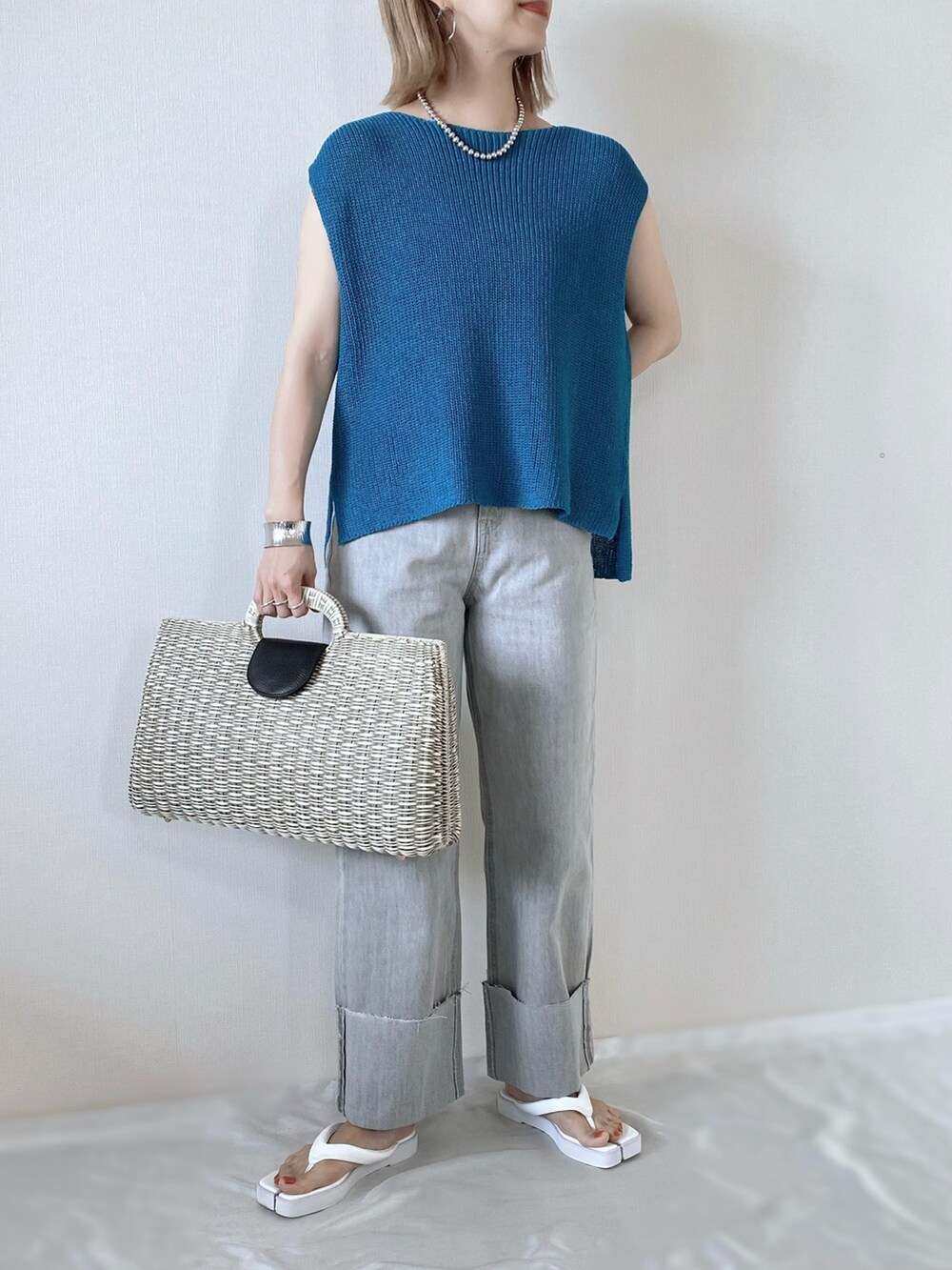 ブルー系のベスト、グレー系のデニムパンツ、ホワイト系のサンダルを着用したレディースの夏コーディネートの5枚目の写真