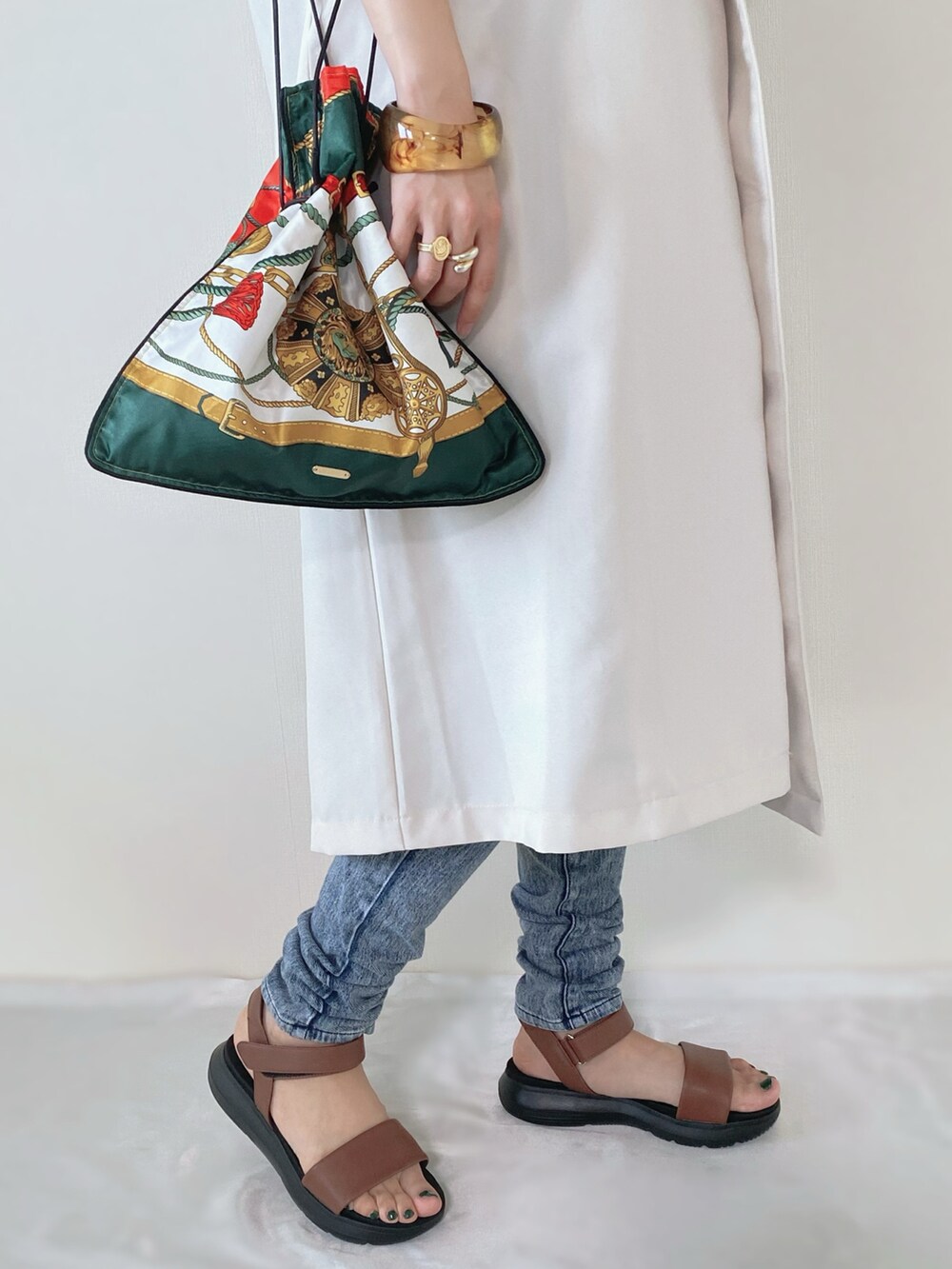 ブラウン系のサンダル、ホワイト系のベスト、その他のバッグを着用したレディースの春コーディネートの3枚目の写真