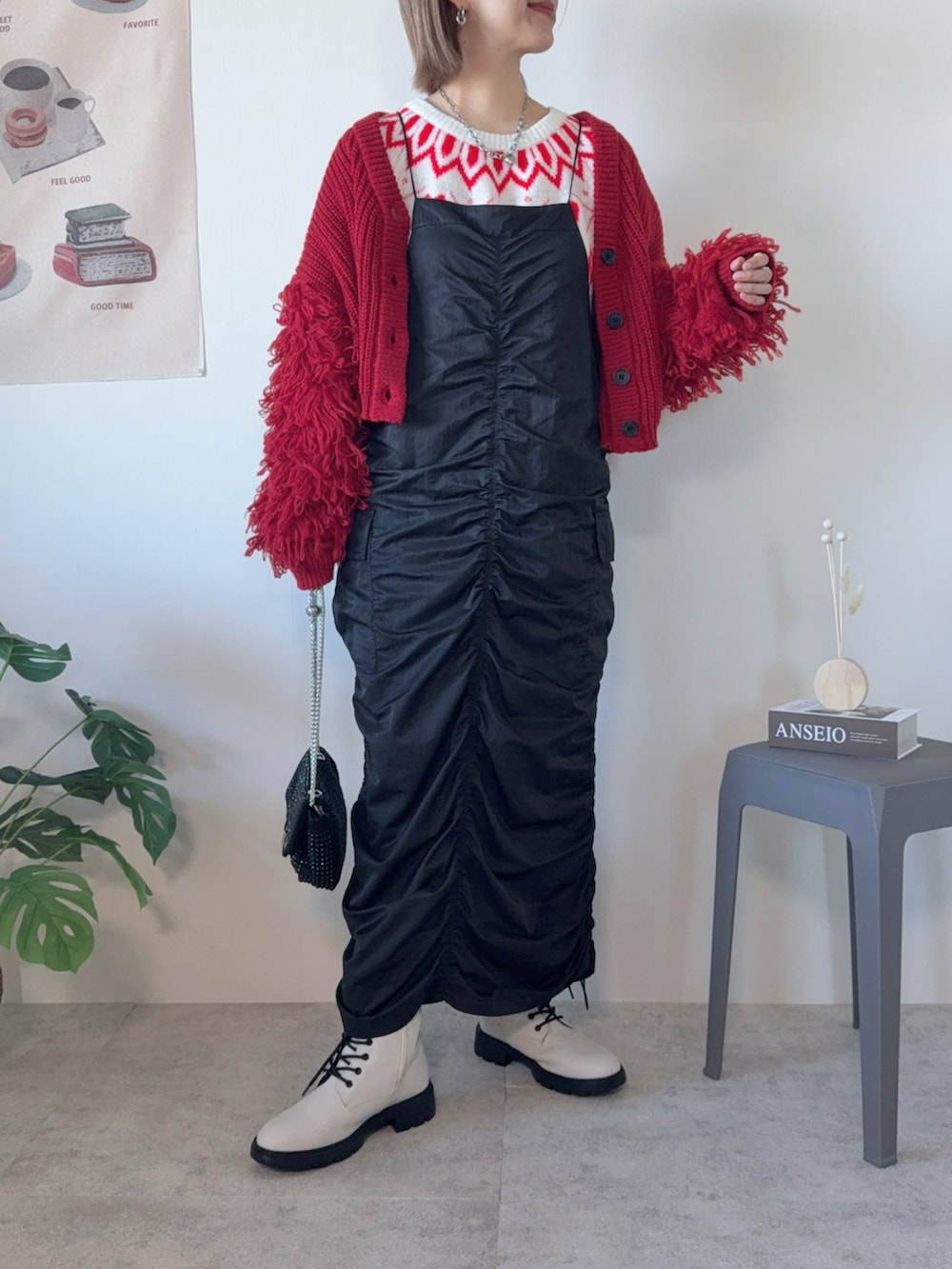 ブラック系のクラッチバッグ、ブラック系のワンピース、ホワイト系のブーツを着用したレディースの冬コーディネートの2枚目の写真