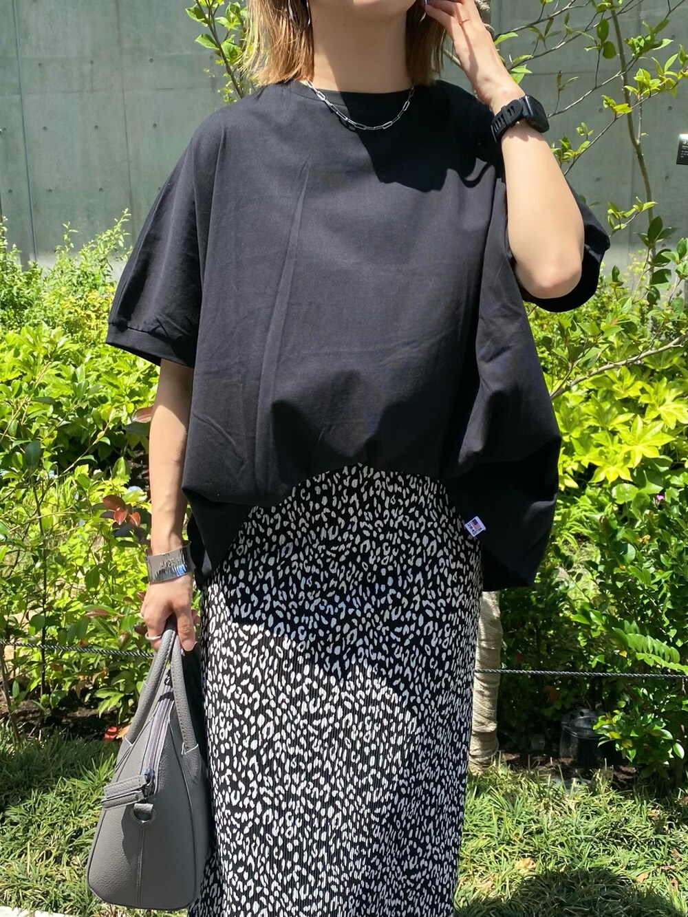 ブラック系のスカート、ブラック系のパンプス、グレー系のハンドバッグを着用したレディースの夏コーディネートの5枚目の写真