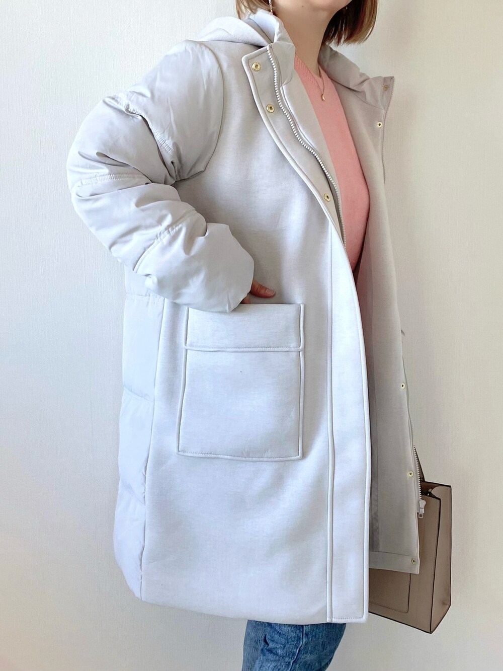 ピンク系のニット/セーター、グレー系のダウンジャケット/コート、ベージュ系のバッグを着用したレディースの冬コーディネートの5枚目の写真