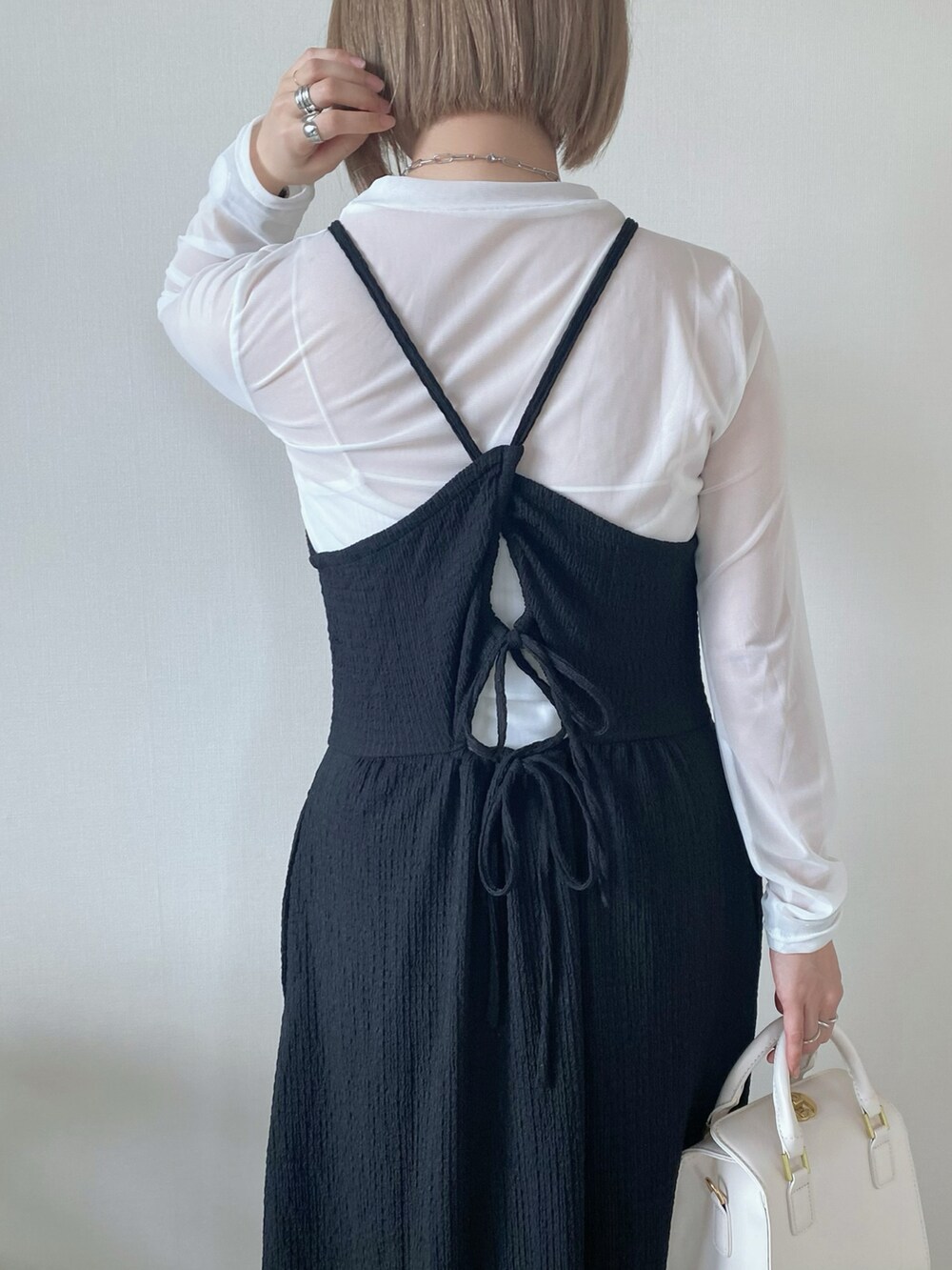 ブラック系のワンピース、ホワイト系のTシャツ/カットソー、ホワイト系のハンドバッグを着用したレディースの春コーディネートの3枚目の写真