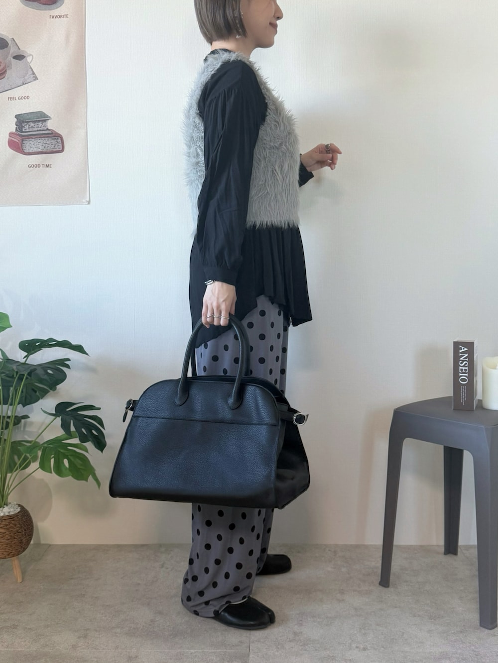 ベージュ系のベスト、ブラック系のボストンバッグ、グレー系のパンツを着用したレディースの冬コーディネートの3枚目の写真