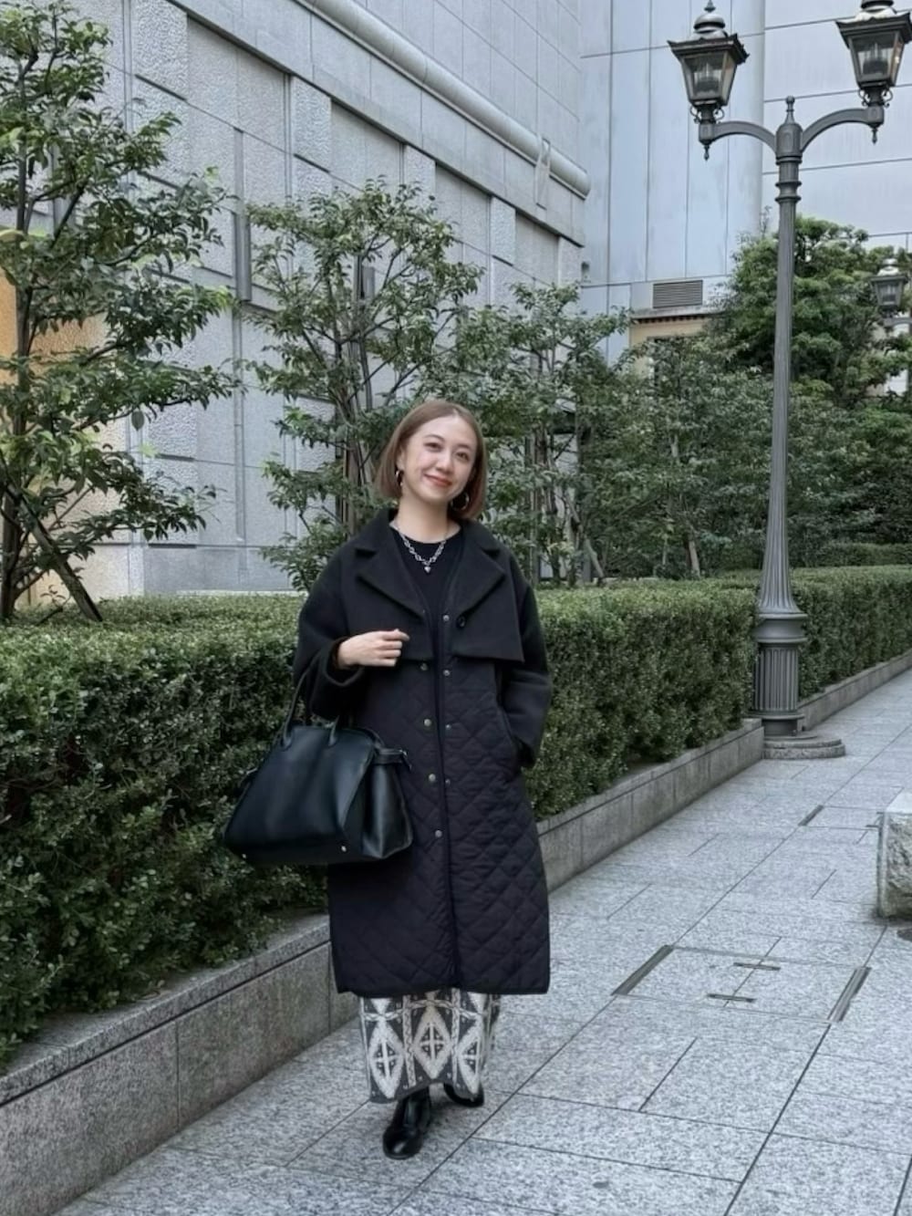 ブラック系のボストンバッグ、グレー系のスカート、ブラック系のブーツを着用したレディースの冬コーディネートの3枚目の写真