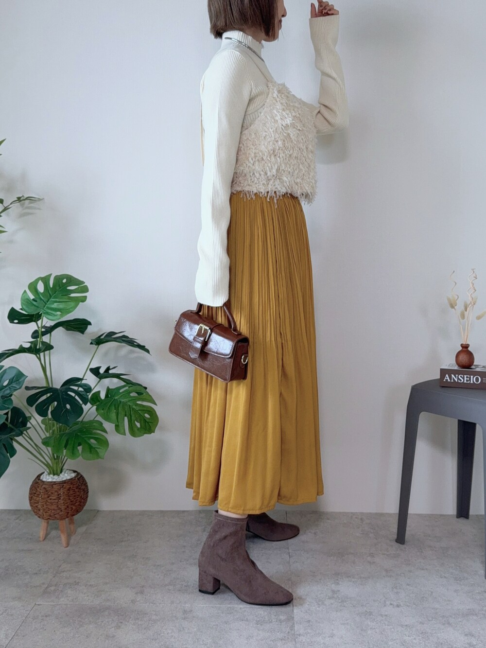 イエロー系のスカート、ブラウン系のハンドバッグ、ホワイト系のシャツ/ブラウスを着用したレディースの秋コーディネートの3枚目の写真