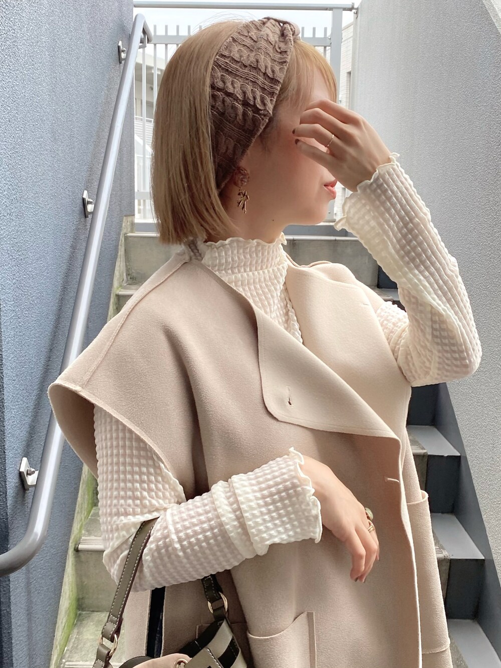 グリーン系のショルダーバッグ、ベージュ系のベスト、ホワイト系のシャツ/ブラウスを着用したレディースの秋コーディネートの3枚目の写真