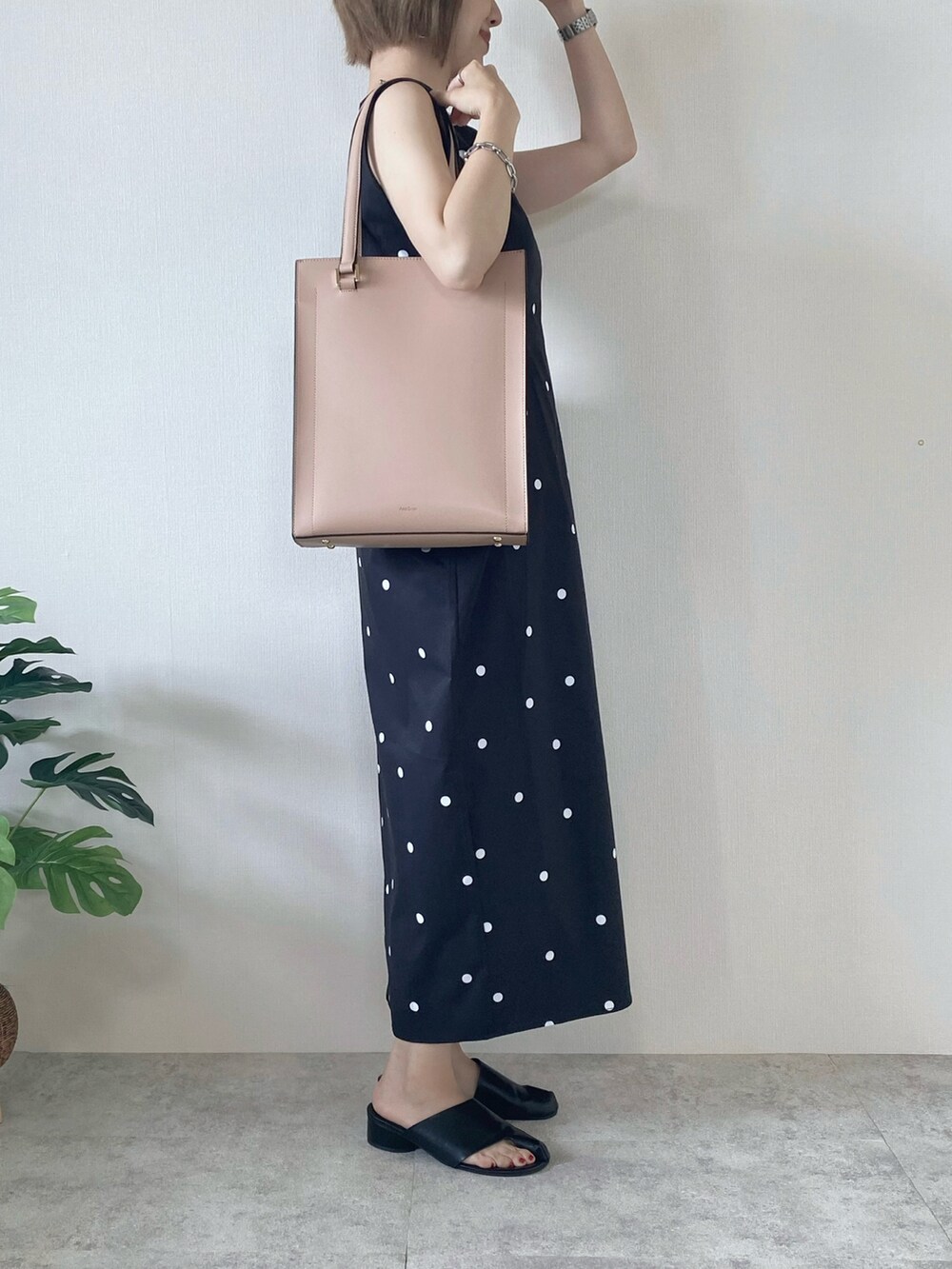 ブラック系のサンダル、ブラック系のワンピース、ピンク系のトートバッグを着用したレディースの夏コーディネートの3枚目の写真