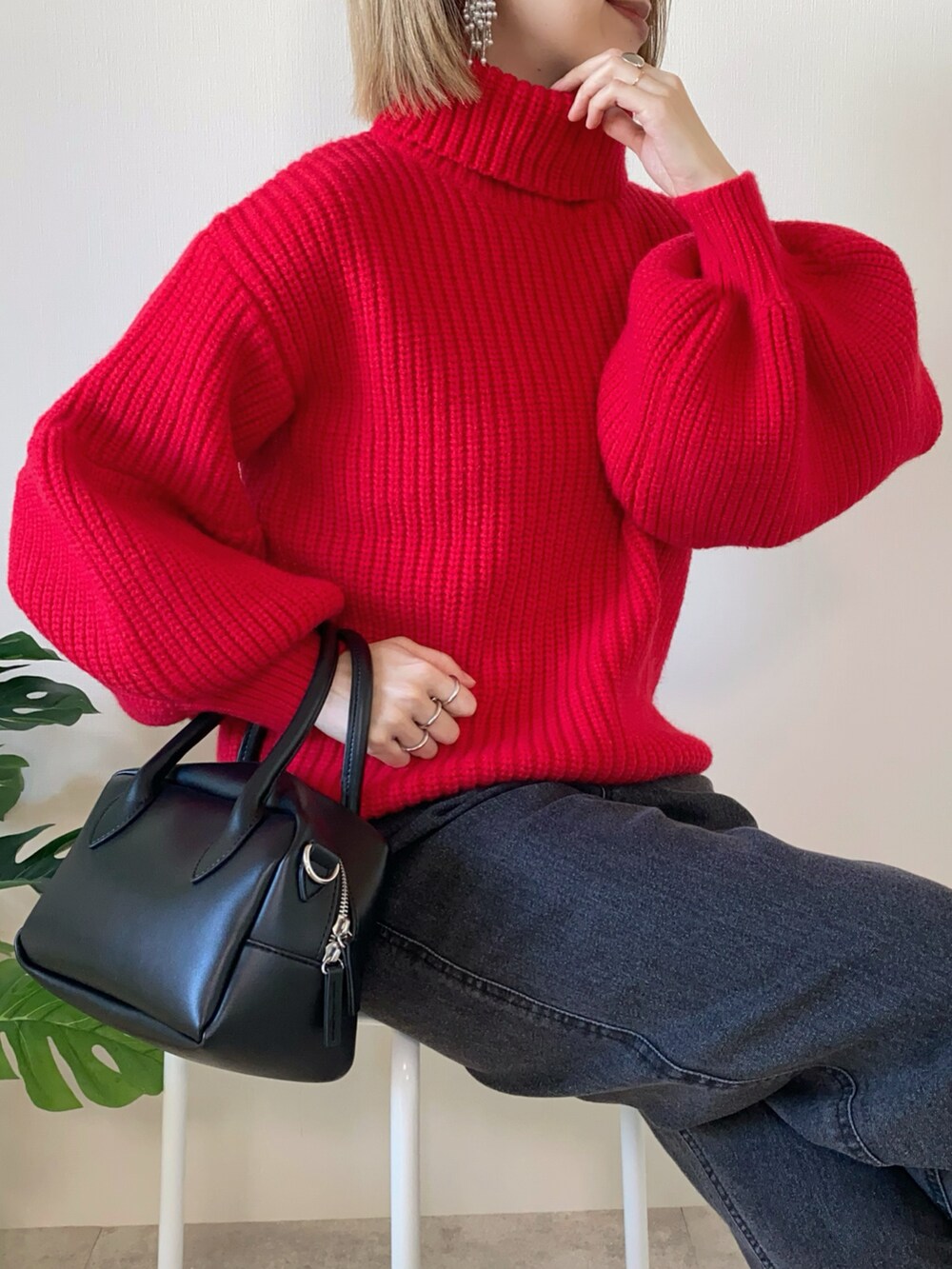 レッド系のニット/セーター、ブラック系のデニムパンツ、ブラック系のバッグを着用したレディースの冬コーディネートの3枚目の写真