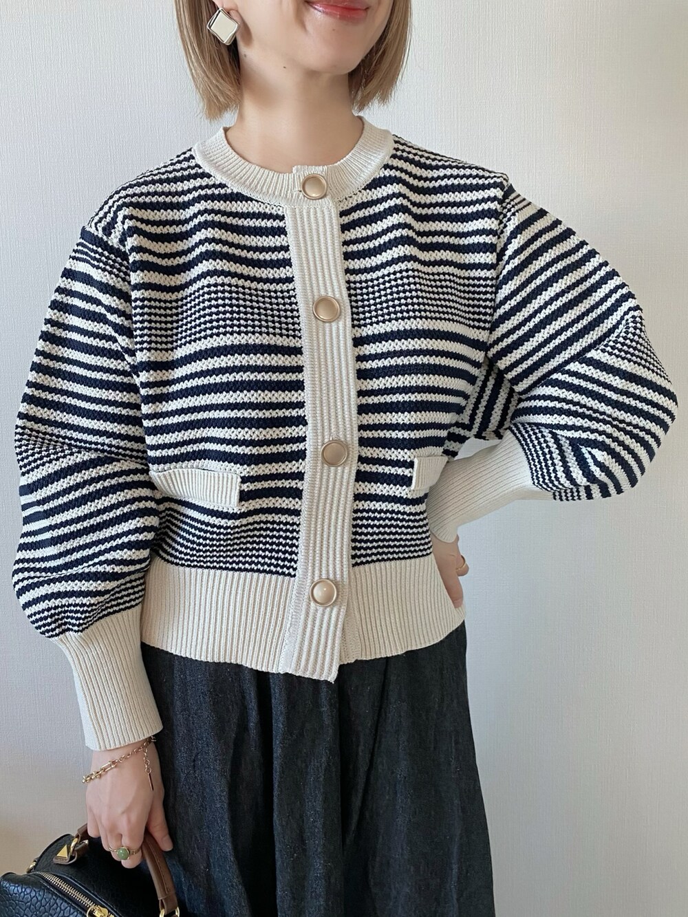 ブラック系のボストンバッグ、ホワイト系のカーディガン/ボレロ、ブラック系のスカートを着用したレディースの冬コーディネートの3枚目の写真