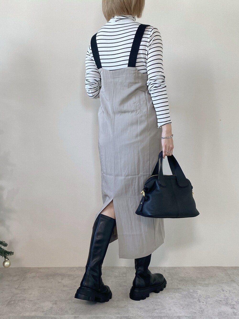 グレー系のジャンパースカート、ブラック系のバッグ、ホワイト系のTシャツ/カットソーを着用したレディースの冬コーディネートの2枚目の写真