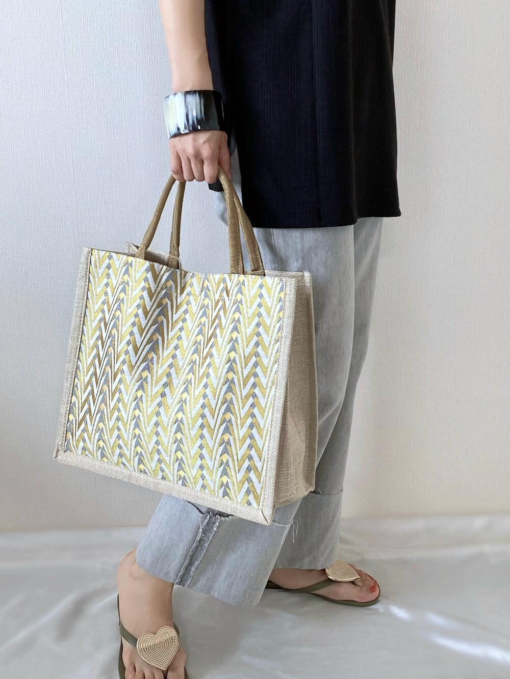 イエロー系のかごバッグ、グレー系のデニムパンツ、グリーン系のサンダルを着用したレディースの夏コーディネートの3枚目の写真