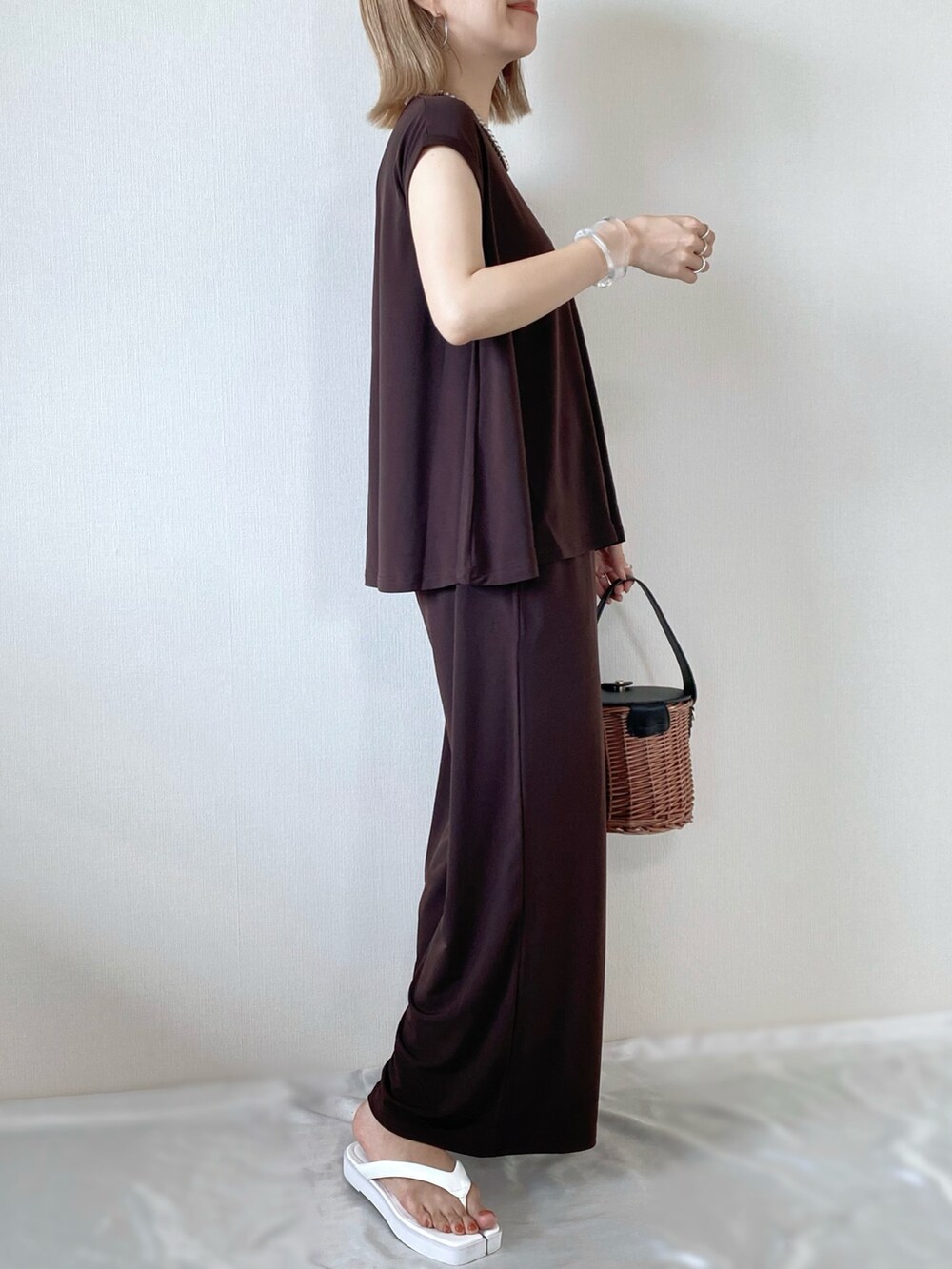 ブラック系のバッグ、ホワイト系のサンダル、ブラウン系のその他トップスを着用したレディースの夏コーディネートの2枚目の写真