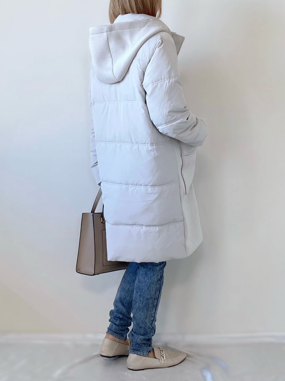 ピンク系のニット/セーター、グレー系のダウンジャケット/コート、ベージュ系のバッグを着用したレディースの冬コーディネートの3枚目の写真