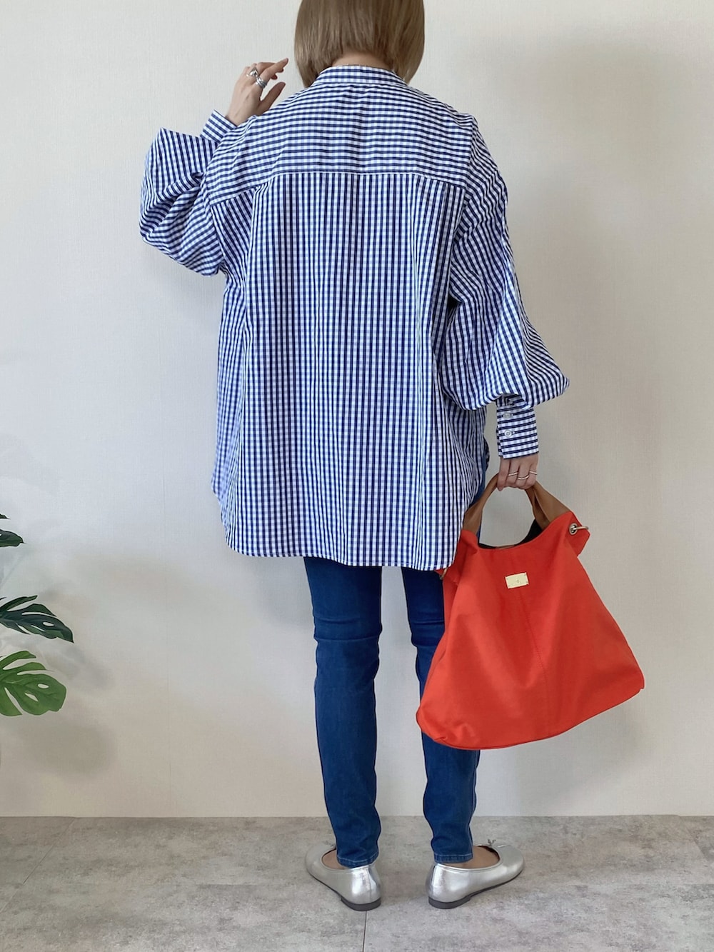 オレンジ系のトートバッグ、シルバー系のバレエシューズ、ブルー系のシャツ/ブラウスを着用したレディースの冬コーディネートの4枚目の写真