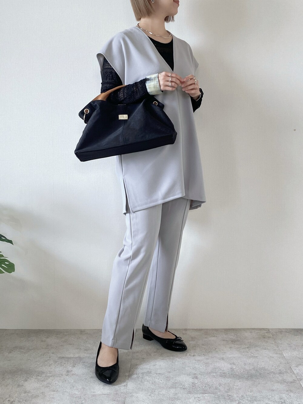ブラック系のトートバッグ、グレー系のアンサンブル、グレー系のその他パンツを着用したレディースの春コーディネートの2枚目の写真