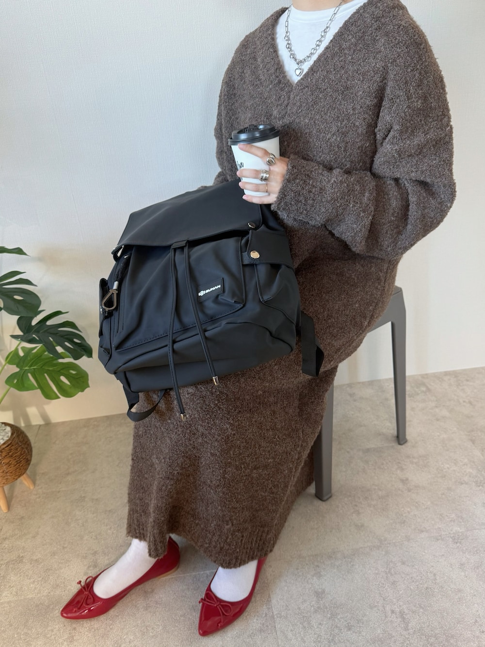 ブラック系のバックパック/リュック、ブラウン系のワンピース、レッド系のバレエシューズを着用したレディースの冬コーディネートの3枚目の写真