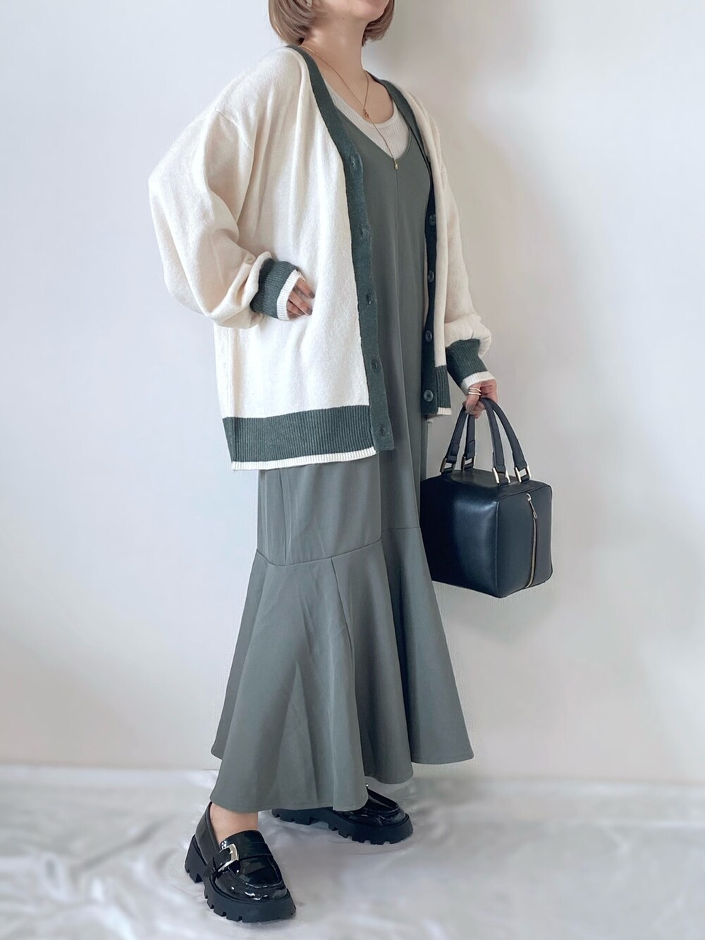 ブラック系のハンドバッグ、ブラック系のローファー、グリーン系のワンピース/ドレスを着用したレディースの秋コーディネートの2枚目の写真