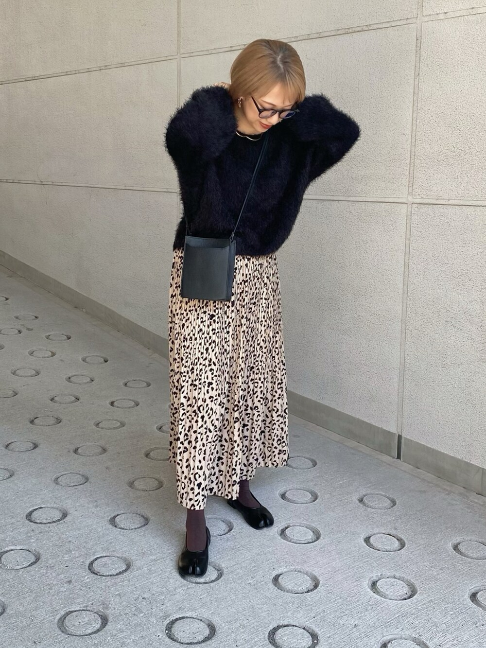 ブラック系のニット/セーター、ブラック系のショルダーバッグ、ベージュ系のスカートを着用したレディースの秋コーディネートの2枚目の写真