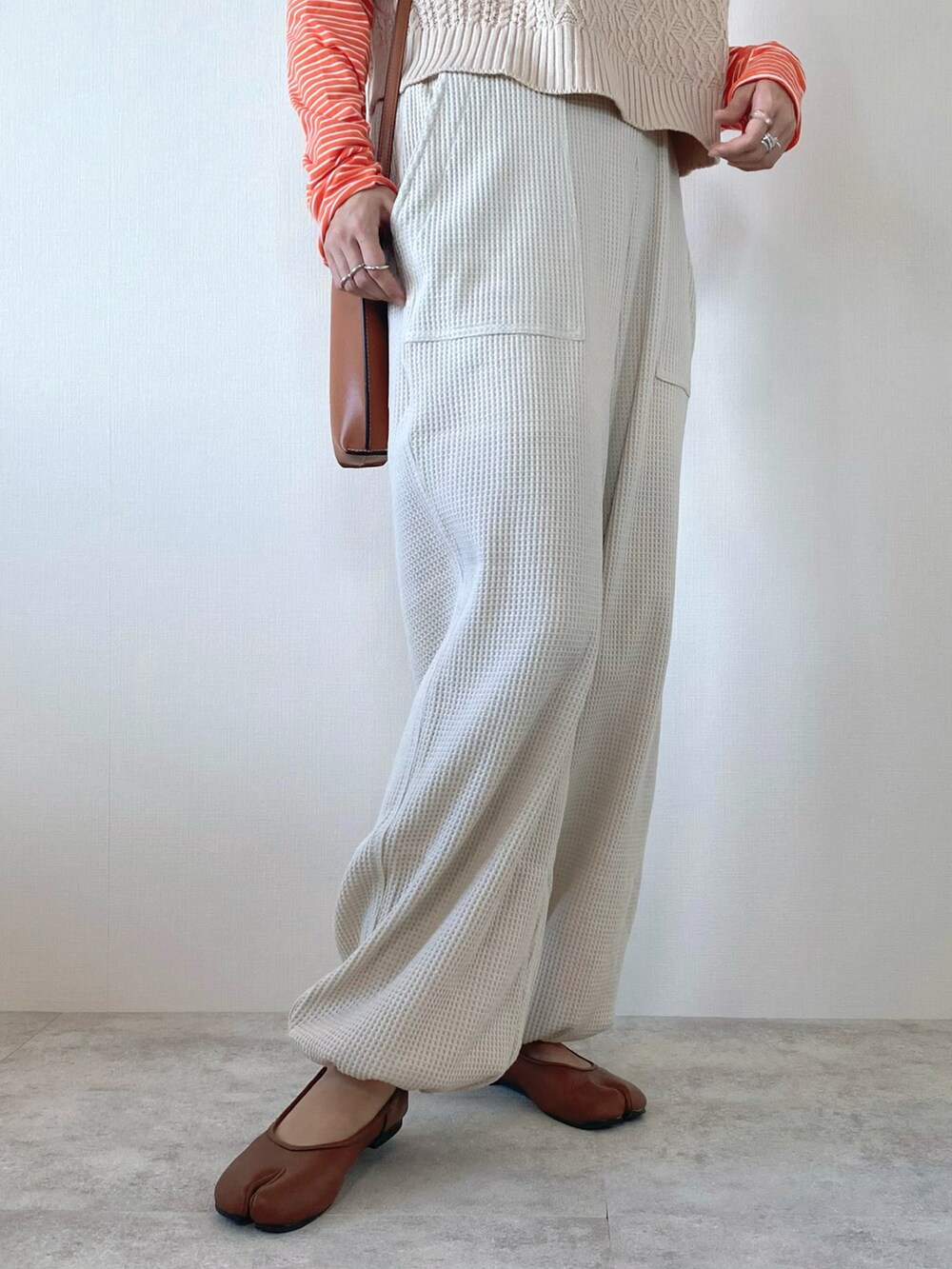 オレンジ系のTシャツ/カットソー、ベージュ系のその他パンツ、ホワイト系のベストを着用したレディースの秋コーディネートの5枚目の写真