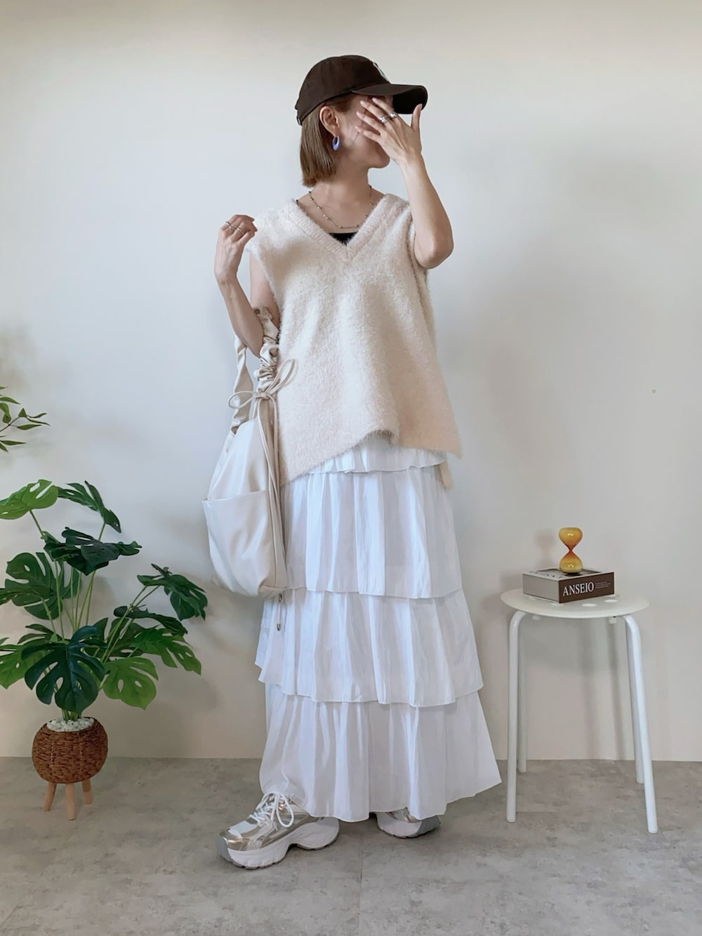 ホワイト系のベスト、ゴールド系のスニーカー、ホワイト系のスカートを着用したレディースの秋コーディネートの2枚目の写真