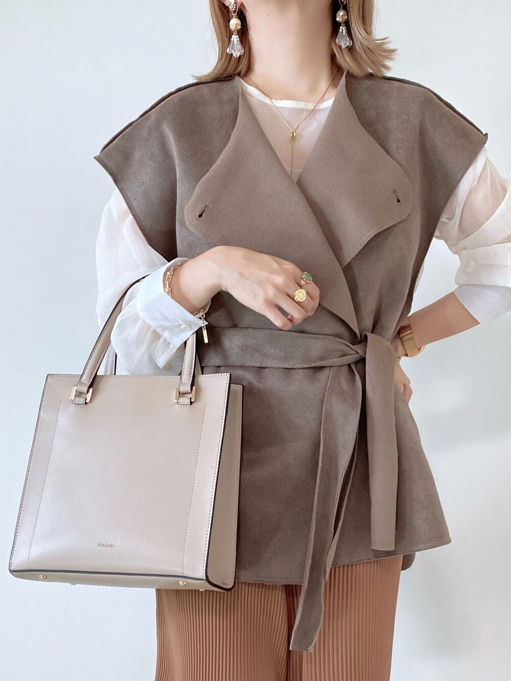 ベージュ系のベスト、ホワイト系のシャツ/ブラウス、ベージュ系のパンツを着用したレディースの秋コーディネートの4枚目の写真