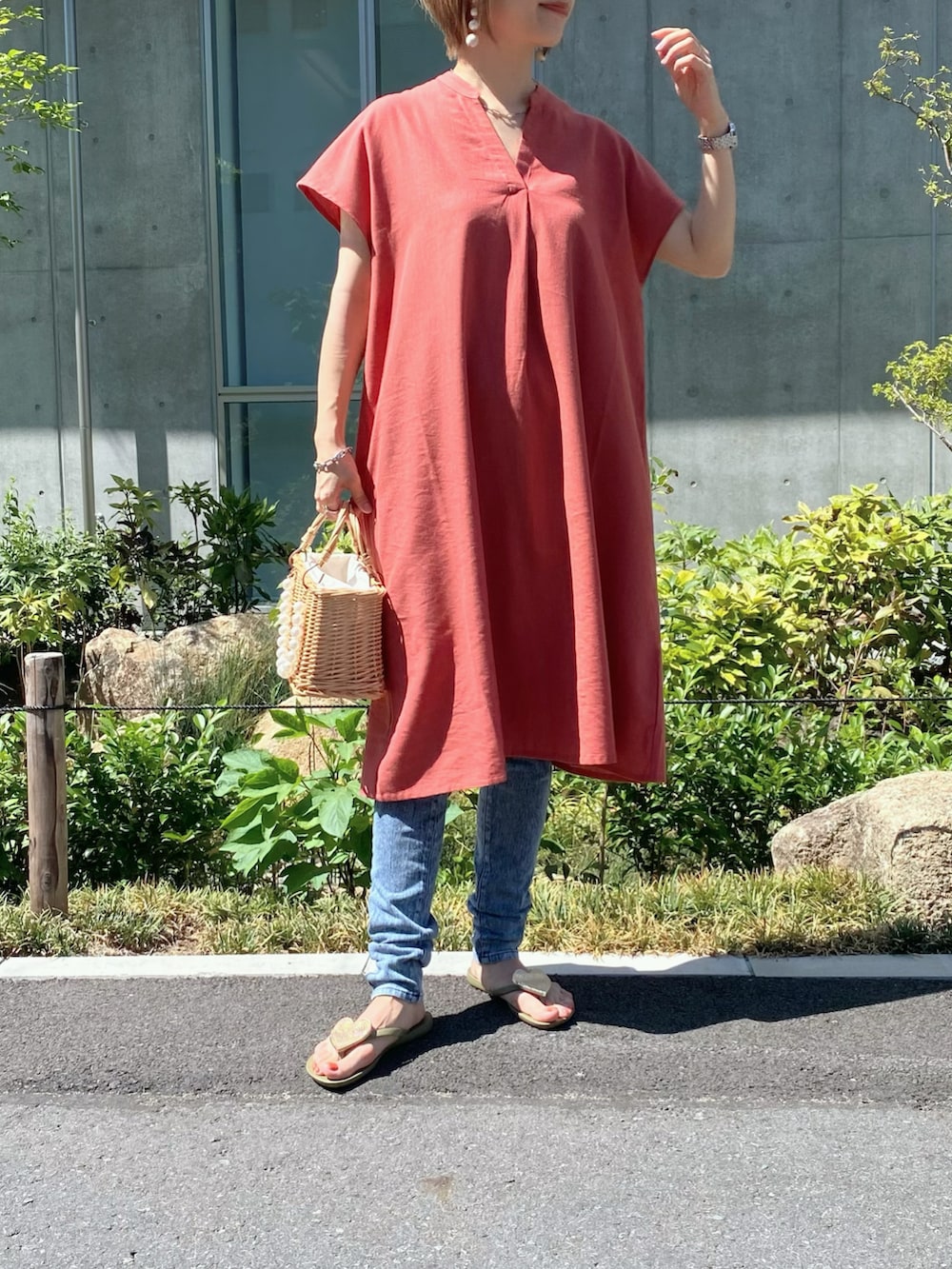 オレンジ系のワンピース、ベージュ系のかごバッグ、グリーン系のサンダルを着用したレディースの夏コーディネートの2枚目の写真