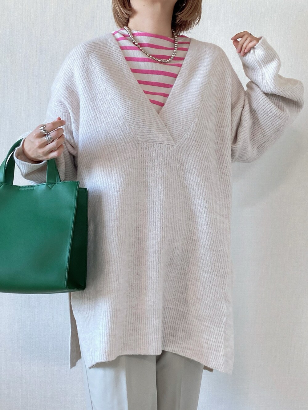 グリーン系のトートバッグ、ベージュ系のニット/セーター、ピンク系のTシャツ/カットソーを着用したレディースの秋コーディネートの3枚目の写真