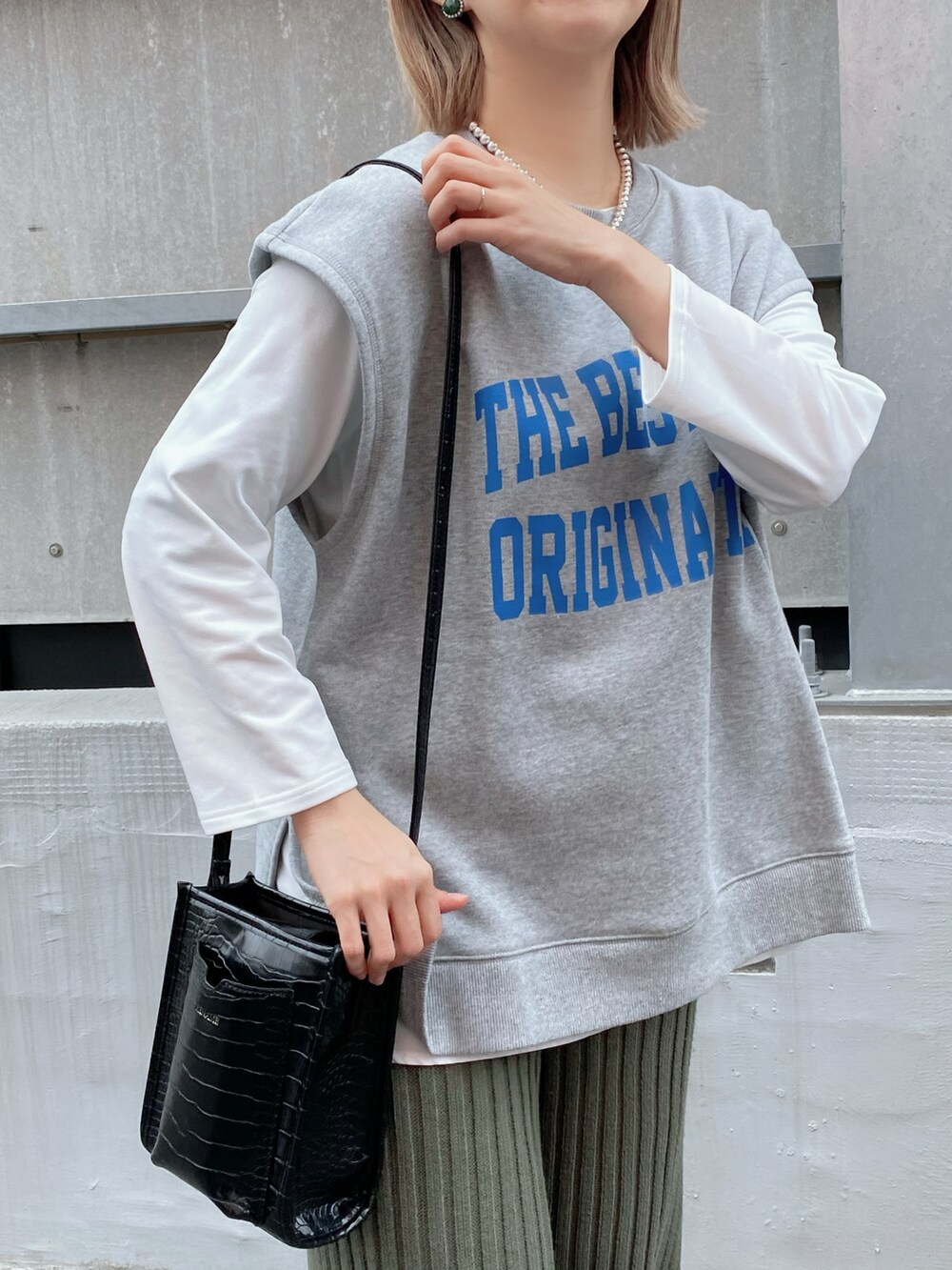 グレー系のベスト、ホワイト系のTシャツ/カットソー、ブラック系のバッグを着用したレディースの冬コーディネートの5枚目の写真