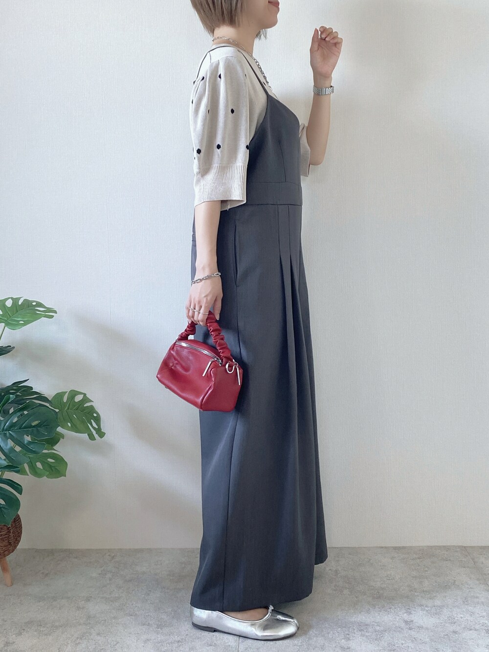 レッド系のボストンバッグ、グレー系のサロペット/オーバーオール、ベージュ系のニット/セーターを着用したレディースの夏コーディネートの2枚目の写真