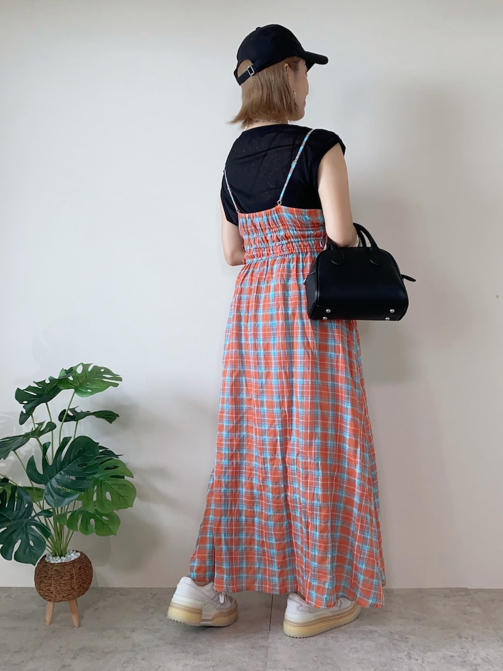 ホワイト系のスニーカー、オレンジ系のワンピース、ブラック系のボストンバッグを着用したレディースの夏コーディネートの4枚目の写真