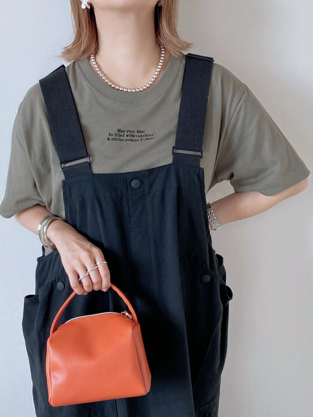 ブラック系のスカート、オレンジ系のバッグ、ブラック系のサンダルを着用したレディースの夏コーディネートの4枚目の写真