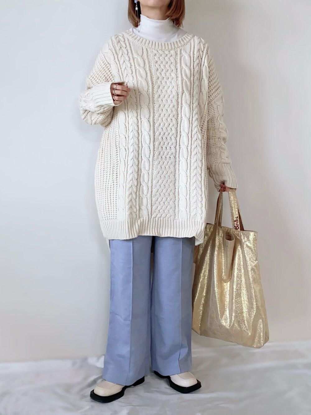 ゴールド系のトートバッグ、ブルー系のパンツ、ベージュ系のローファーを着用したレディースの冬コーディネートの2枚目の写真