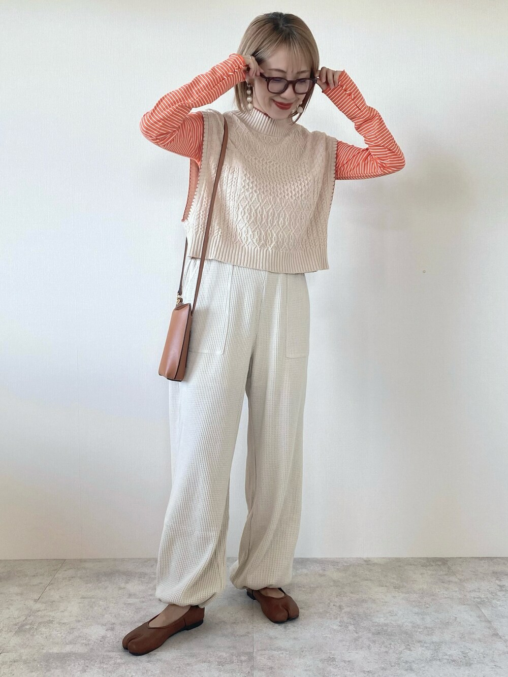 オレンジ系のTシャツ/カットソー、ベージュ系のその他パンツ、ホワイト系のベストを着用したレディースの秋コーディネートの2枚目の写真