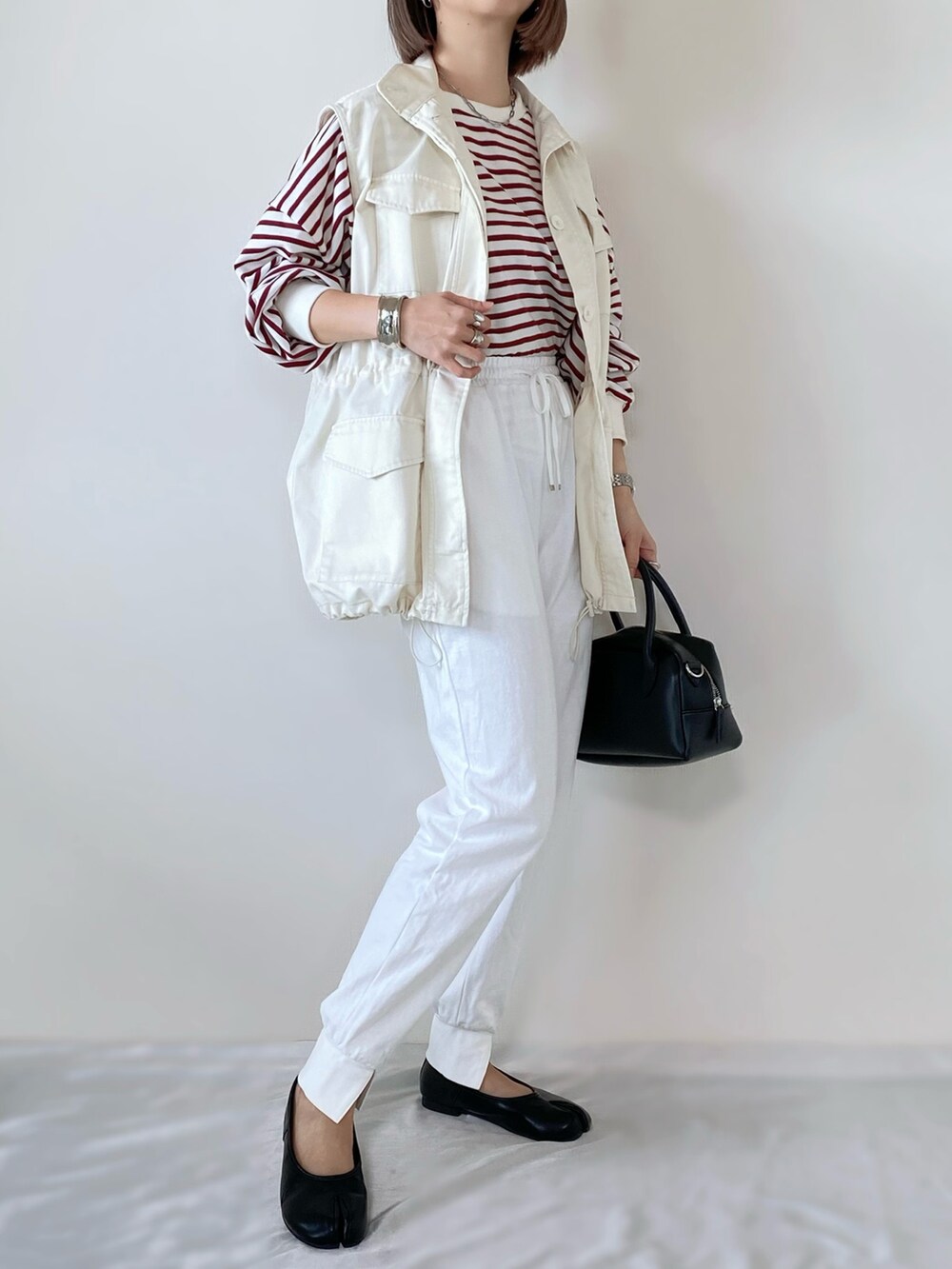 レッド系のTシャツ/カットソー、ホワイト系のベスト、ホワイト系のその他パンツを着用したレディースの冬コーディネートの2枚目の写真