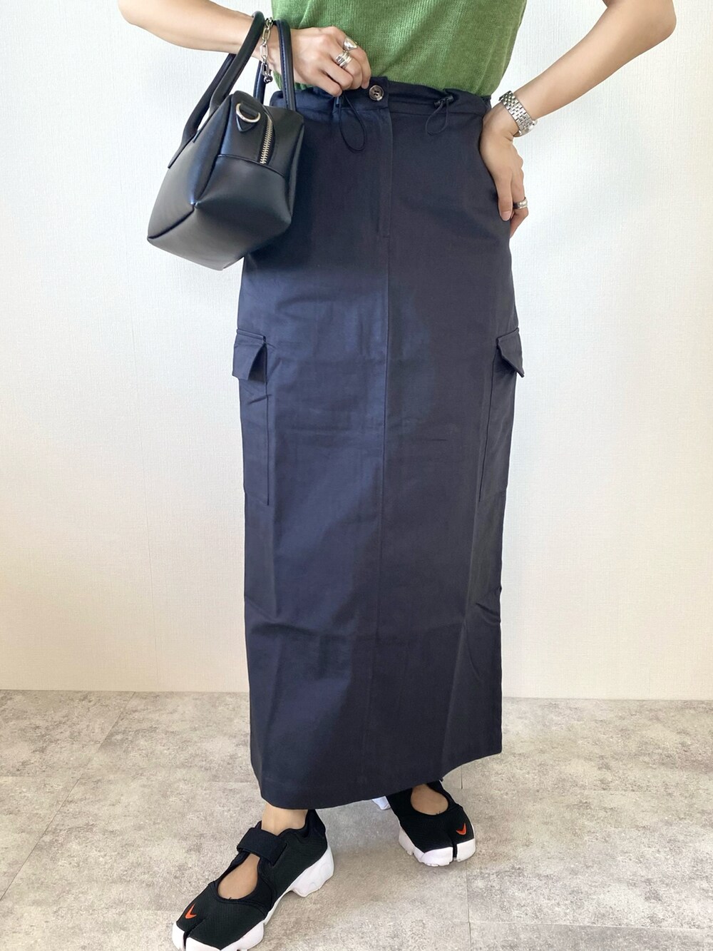 ブルー系のベスト、グリーン系のニット/セーター、グレー系のスカートを着用したレディースの秋コーディネートの5枚目の写真