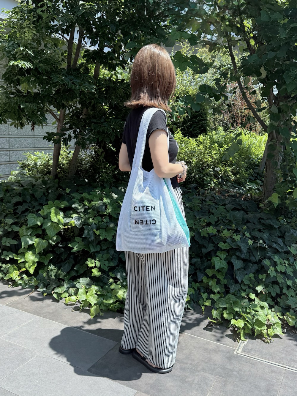 ホワイト系のその他パンツ、ブラック系のTシャツ/カットソー、ホワイト系のトートバッグを着用したレディースの夏コーディネートの3枚目の写真