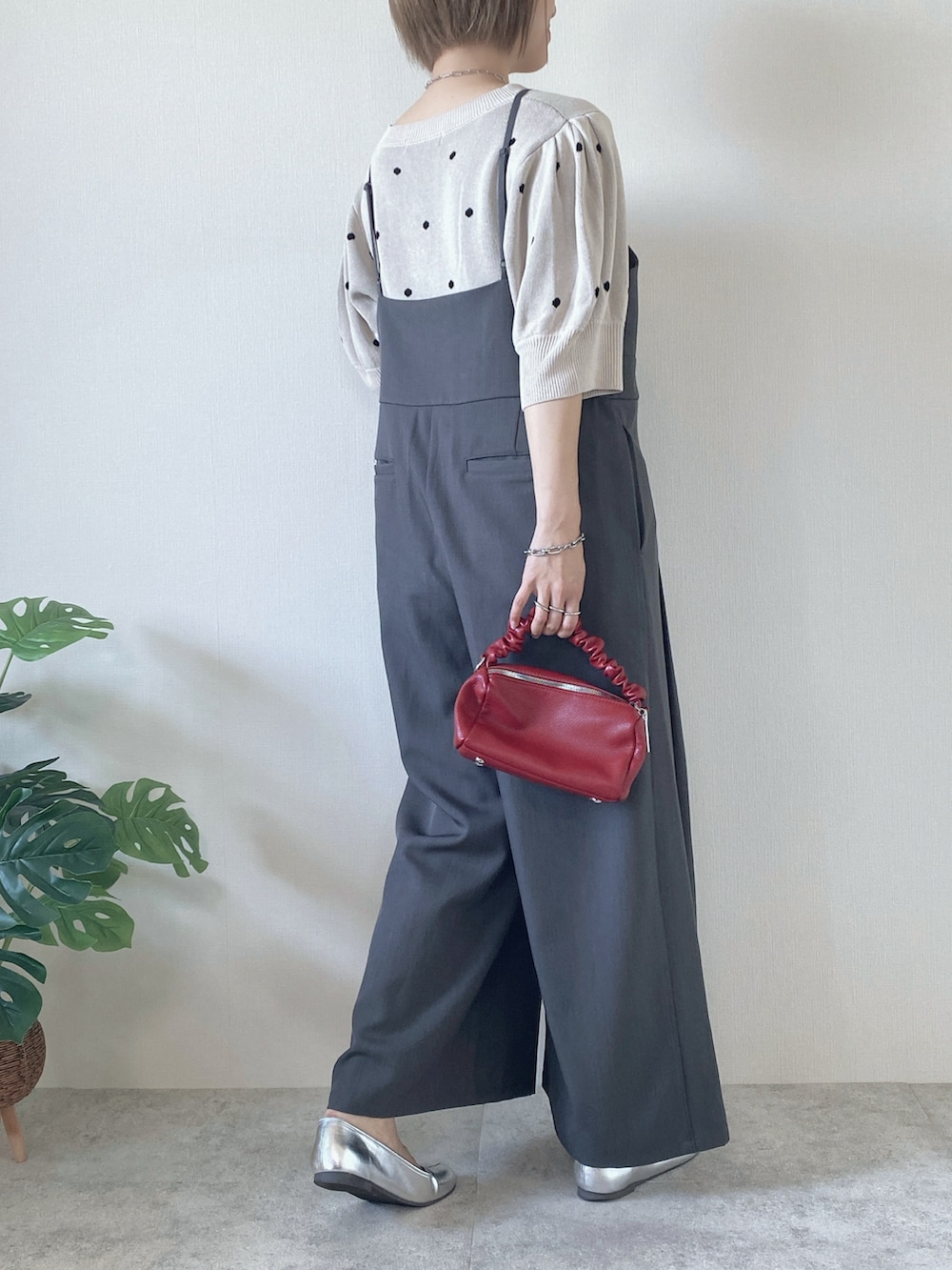 レッド系のボストンバッグ、グレー系のサロペット/オーバーオール、ベージュ系のニット/セーターを着用したレディースの夏コーディネートの3枚目の写真