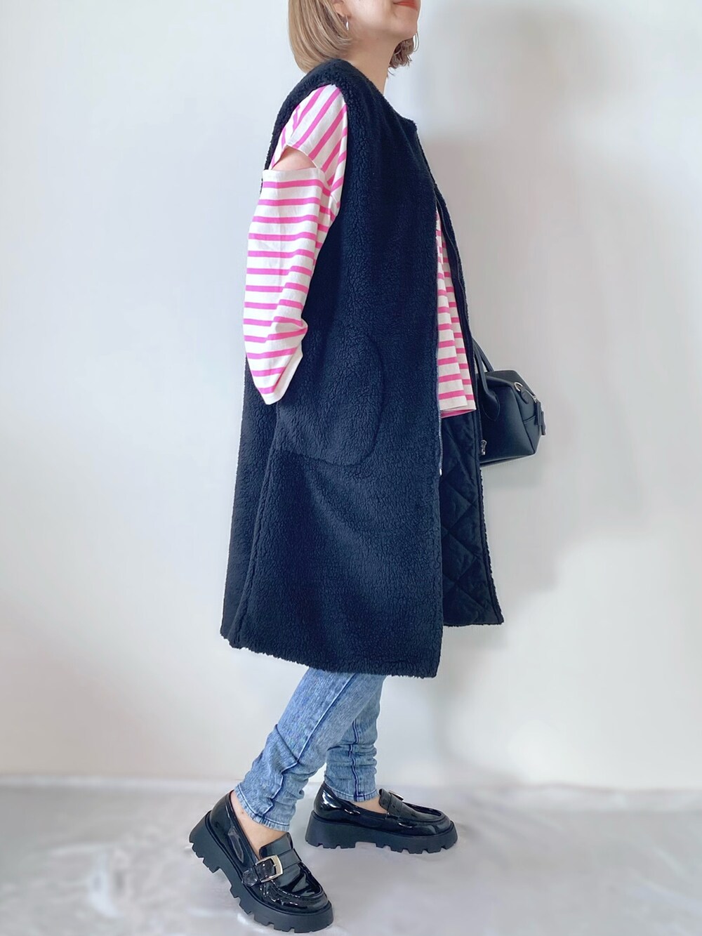 ブラック系のベスト、ピンク系のTシャツ/カットソー、ブラック系のバッグを着用したレディースの秋コーディネートの2枚目の写真