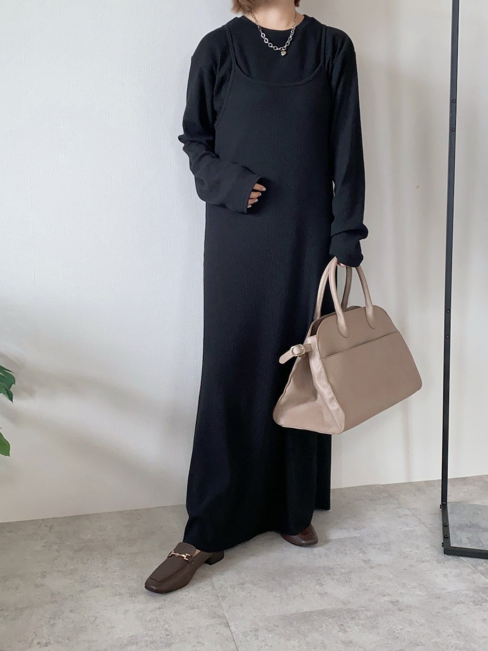 ブラック系のワンピース、ベージュ系のボストンバッグ、ブラウン系のローファーを着用したレディースの秋コーディネートの3枚目の写真