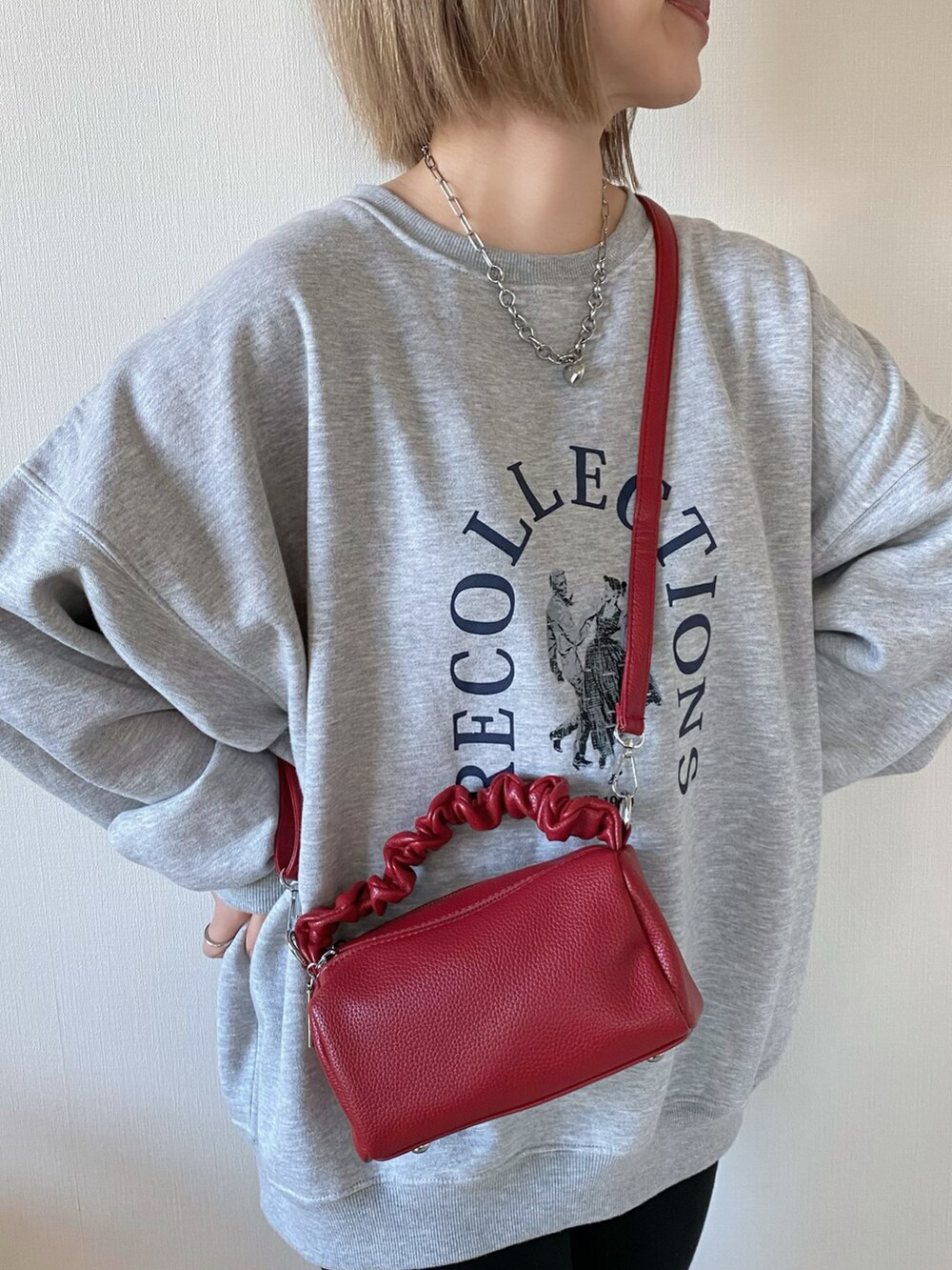 グレー系のスウェット、レッド系のボストンバッグ、ブラック系のパンプスを着用したレディースの冬コーディネートの2枚目の写真