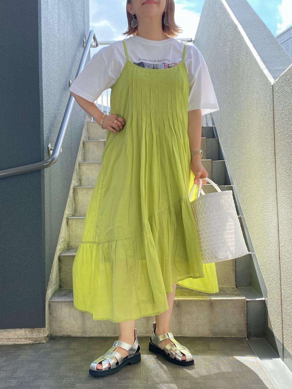 イエロー系のワンピース、ホワイト系のかごバッグ、ホワイト系のTシャツ/カットソーを着用したレディースの夏コーディネートの3枚目の写真
