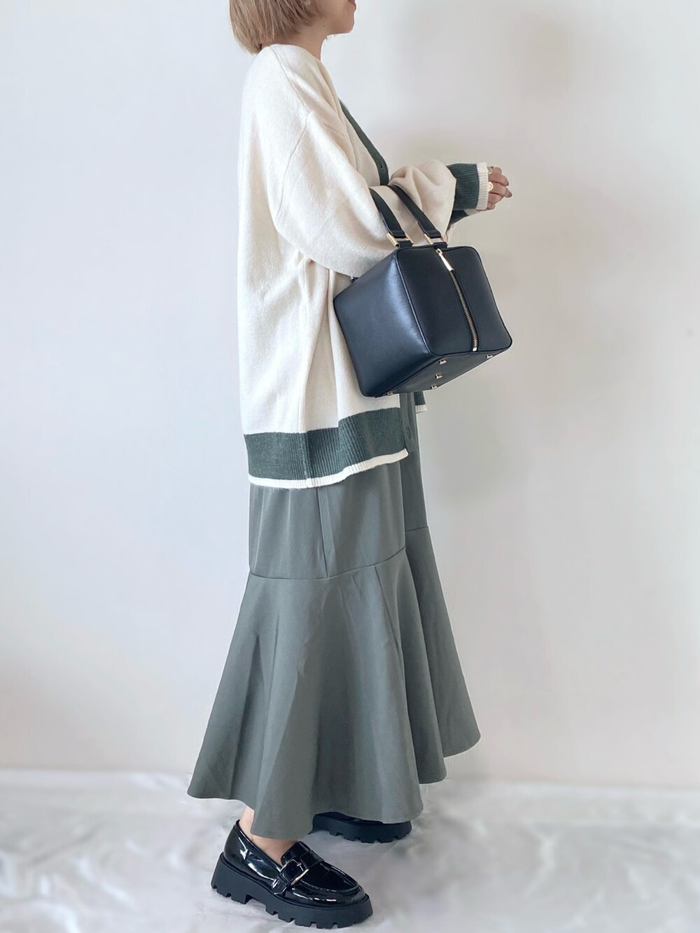 ブラック系のハンドバッグ、ブラック系のローファー、グリーン系のワンピース/ドレスを着用したレディースの秋コーディネートの3枚目の写真