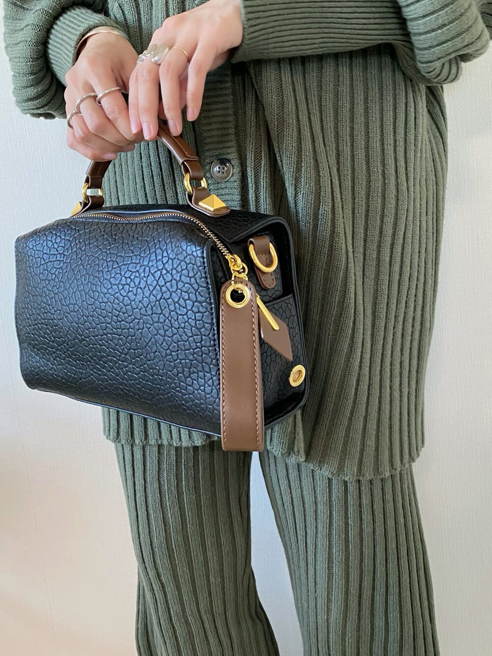 ブラック系のボストンバッグ、グリーン系のニット/セーター、ブラック系のパンプスを着用したレディースの冬コーディネートの4枚目の写真