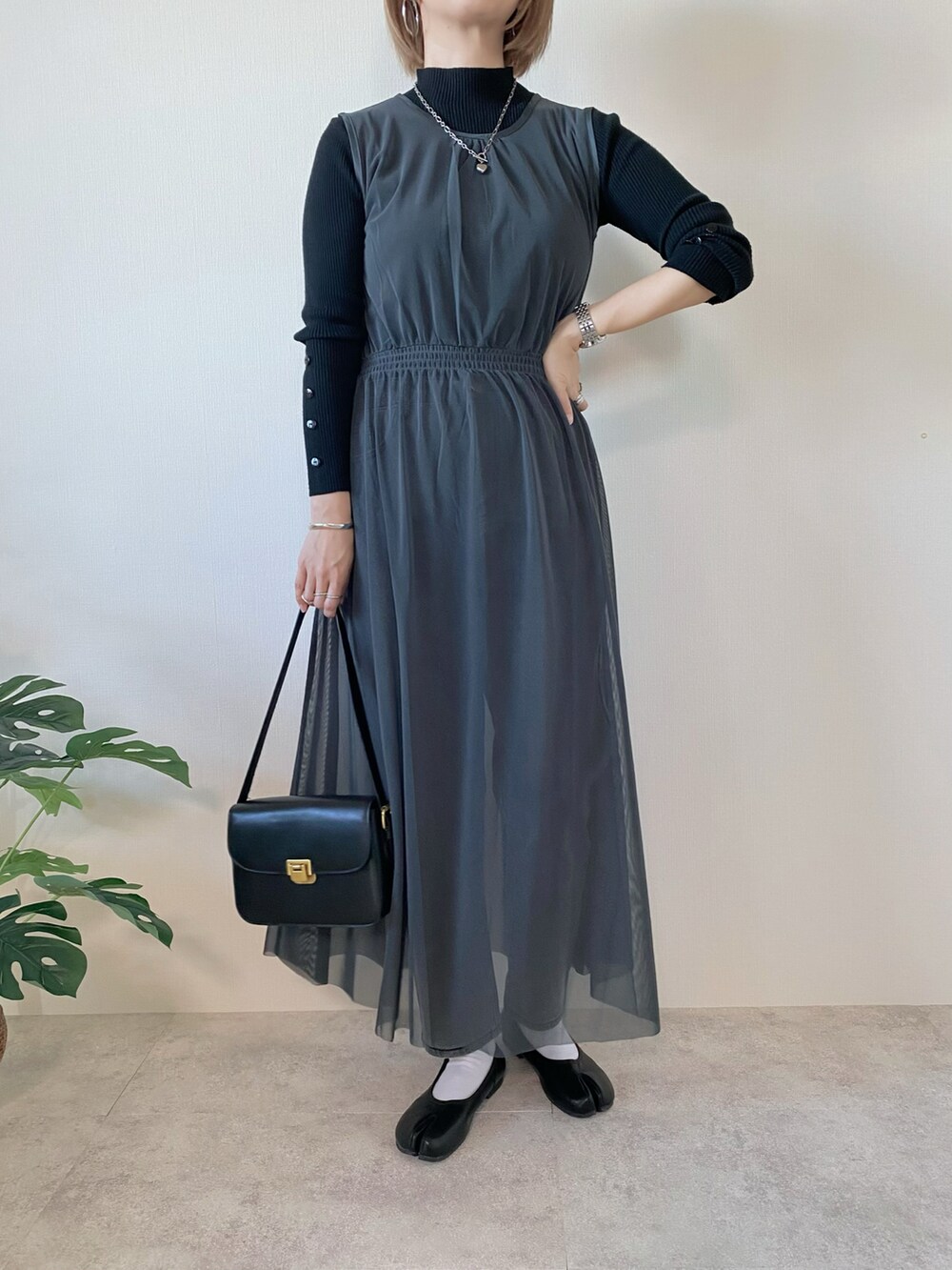 ブラック系のショルダーバッグ、グレー系のワンピース、ブラック系のニット/セーターを着用したレディースの秋コーディネートの4枚目の写真