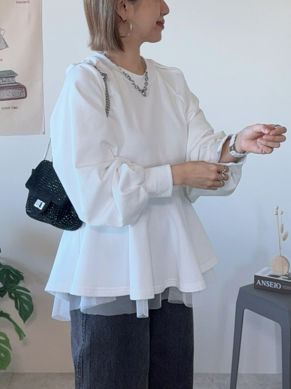 ホワイト系のスウェット、ブラック系のデニムパンツ、ブラック系のクラッチバッグを着用したレディースの冬コーディネートの3枚目の写真