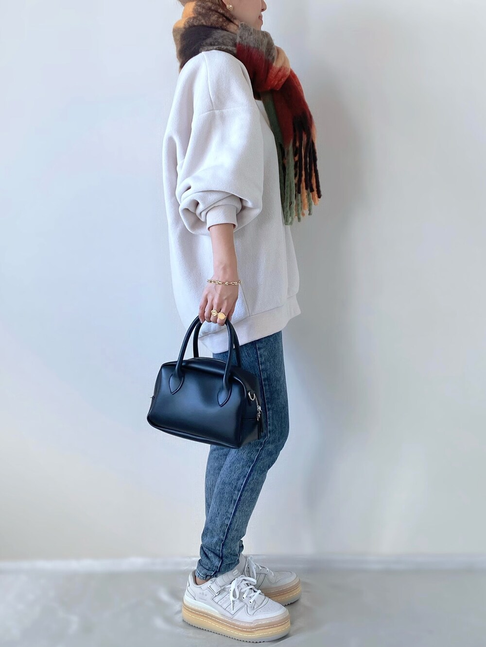 ホワイト系のスウェット、ホワイト系のスニーカー、ブラック系のバッグを着用したレディースの冬コーディネートの2枚目の写真