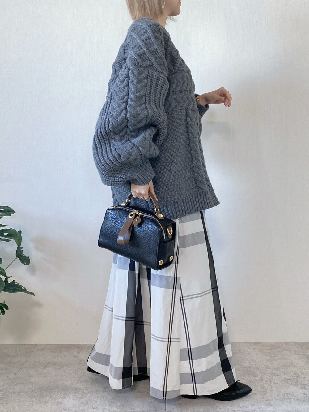 グレー系のニット/セーター、ブラック系のボストンバッグ、ホワイト系のスカートを着用したレディースの冬コーディネートの2枚目の写真
