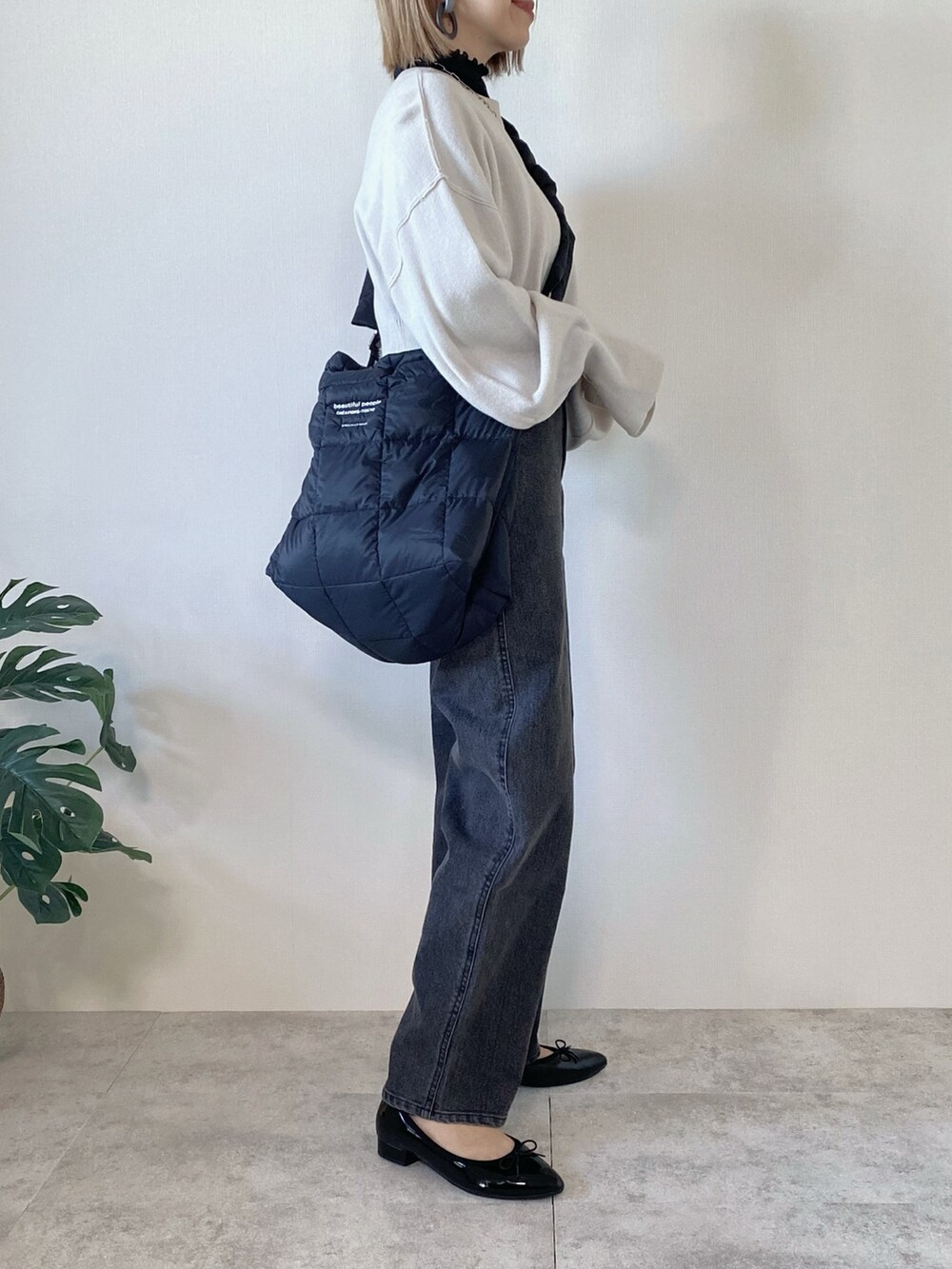 ブラック系のデニムパンツ、ブラック系のショルダーバッグ、ブラック系のパンプスを着用したレディースの冬コーディネートの2枚目の写真