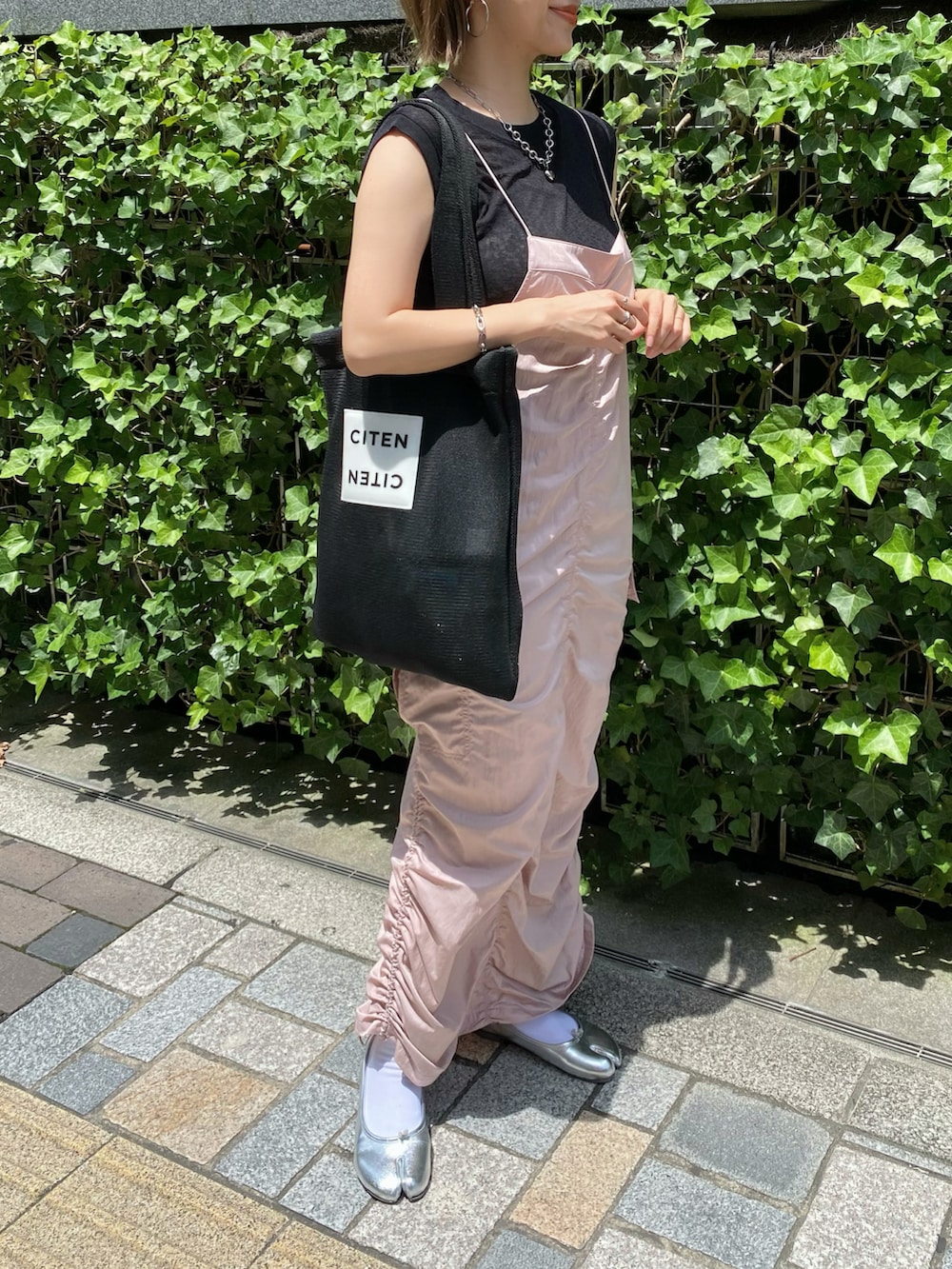 ブラック系のトートバッグ、ピンク系のワンピース、シルバー系のバレエシューズを着用したレディースの夏コーディネートの2枚目の写真